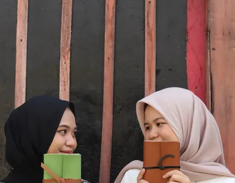 Dua Gadis Saling Berpandangan Memegang Jurnal Hibrkraft
