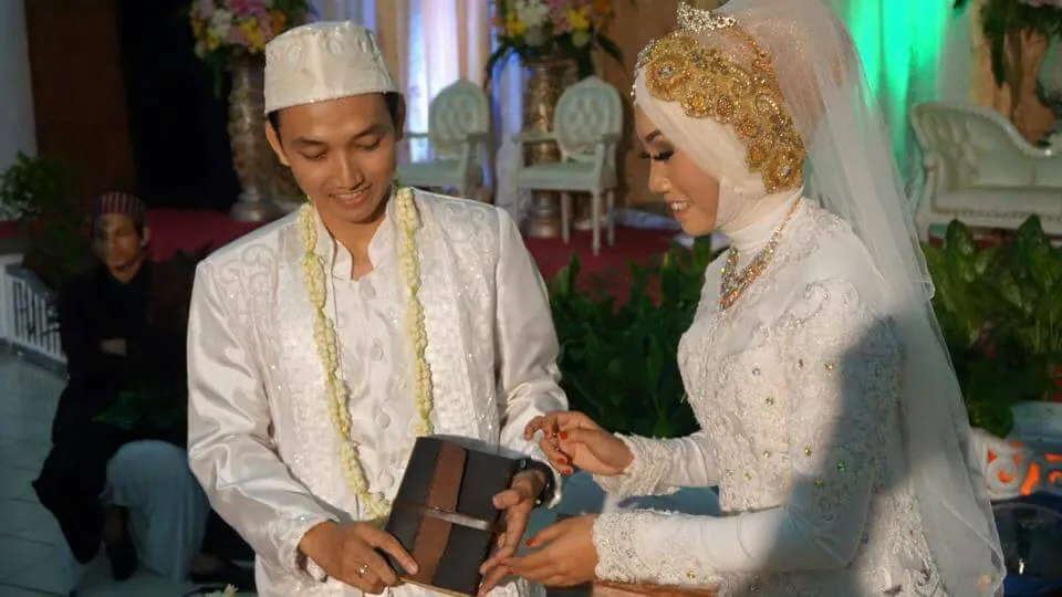 Pengantin pria menyerahkan kotak kulit berisi mas kawin kepada pengantin wanita saat prosesi akad nikah