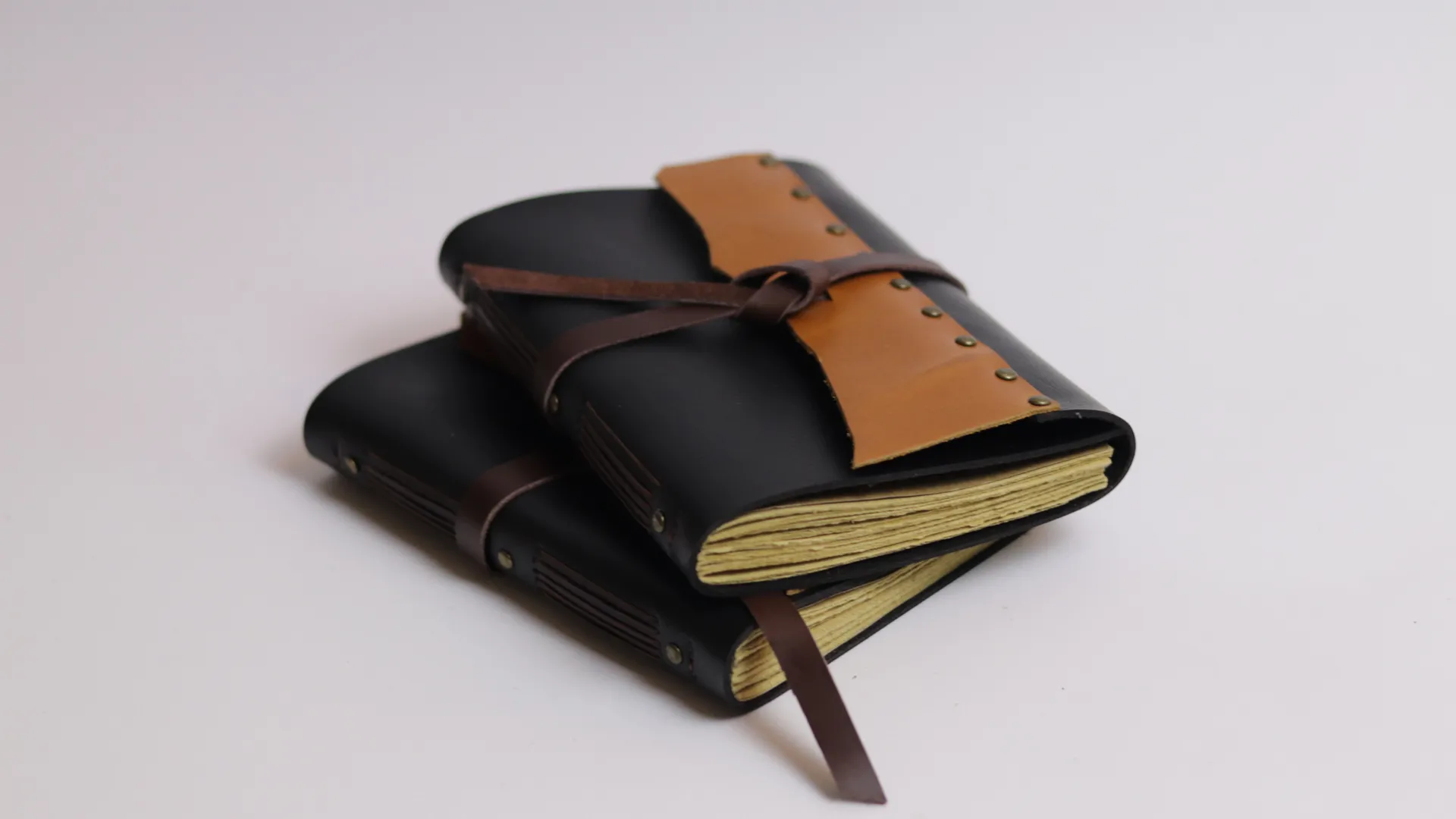Two Black And Tan Leather Notebooks Stacked