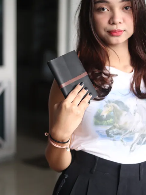 Wanita memegang buku catatan kustom dengan penutup kulit, menunjukkan estetika jurnal premium.