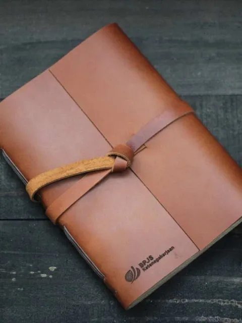 Jurnal kulit cokelat dengan detail jahitan yang rapi, mencerminkan kualitas pengerjaan.