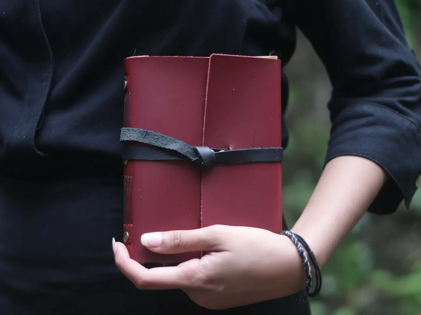 Detail sampul jurnal kulit berwarna burgundy dengan tali pengikat, menonjolkan keahlian dan kualitas material.