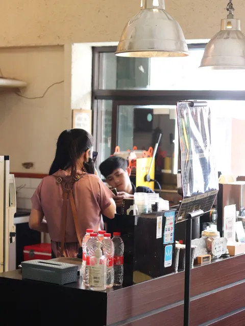 Meja kasir dengan staf melayani pelanggan, menampilkan produk notebook