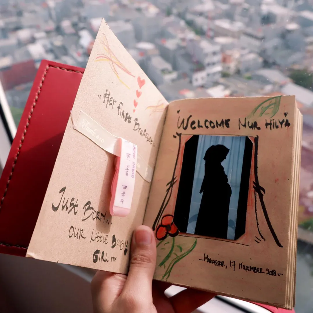 Sebuah jurnal bayi buatan tangan yang dihias, menunjukkan penggunaan buku catatan untuk melestarikan kenangan paling berharga.