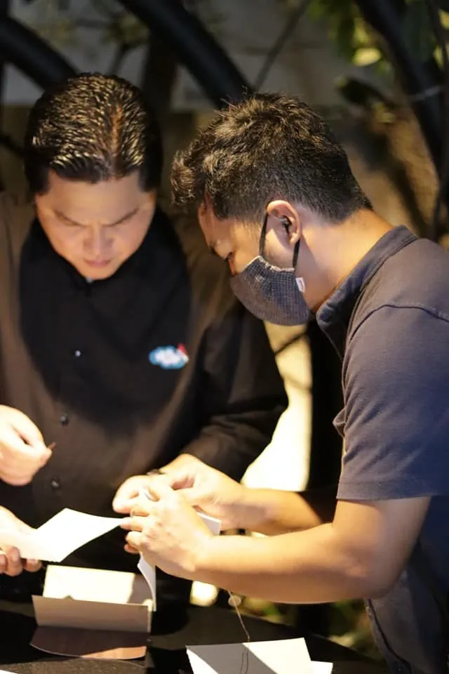 Menteri BUMN Erick Thohir bersama Ibrahim Anwar dari Hibrkraft, keduanya fokus mencoba proses menjahit sebuah jurnal kulit.