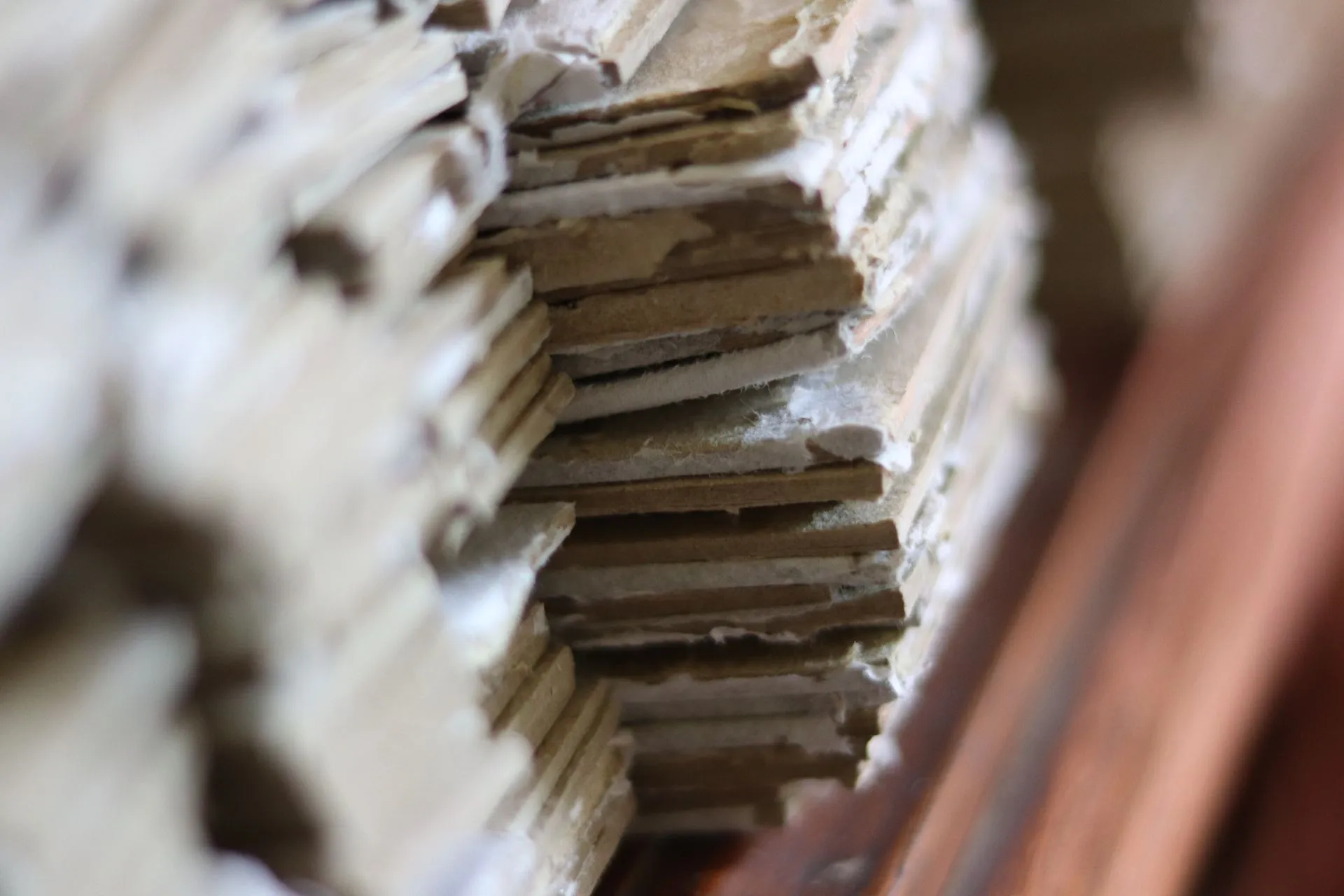 Tampilan close-up lain dari tumpukan karton berlapis yang menunjukkan tekstur kasar di tepinya.