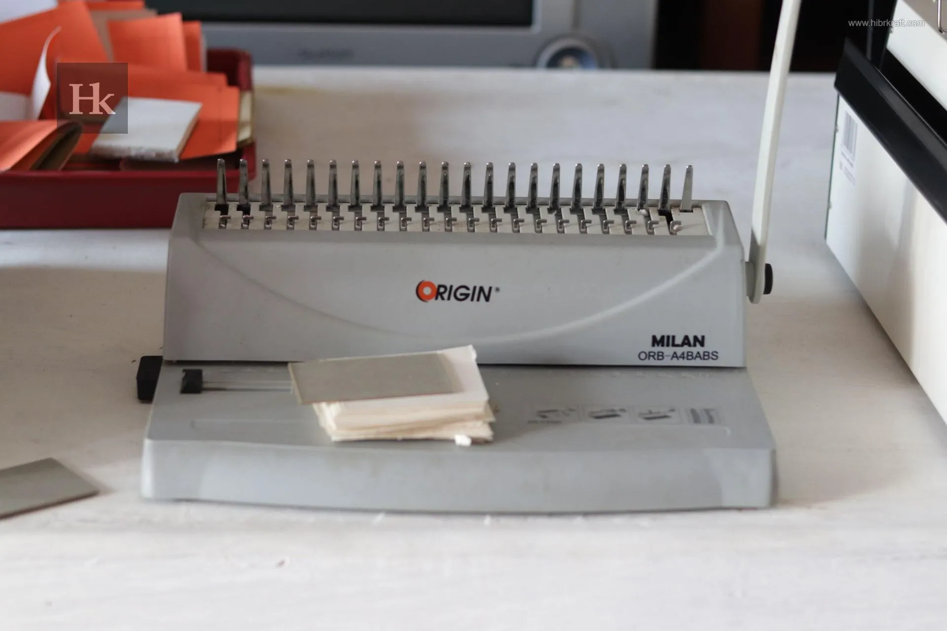 Mesin binding manual berwarna krem dengan sisir plastik hitam, menampilkan kesederhanaan dan ketangguhan dalam proses penjilidan buku.