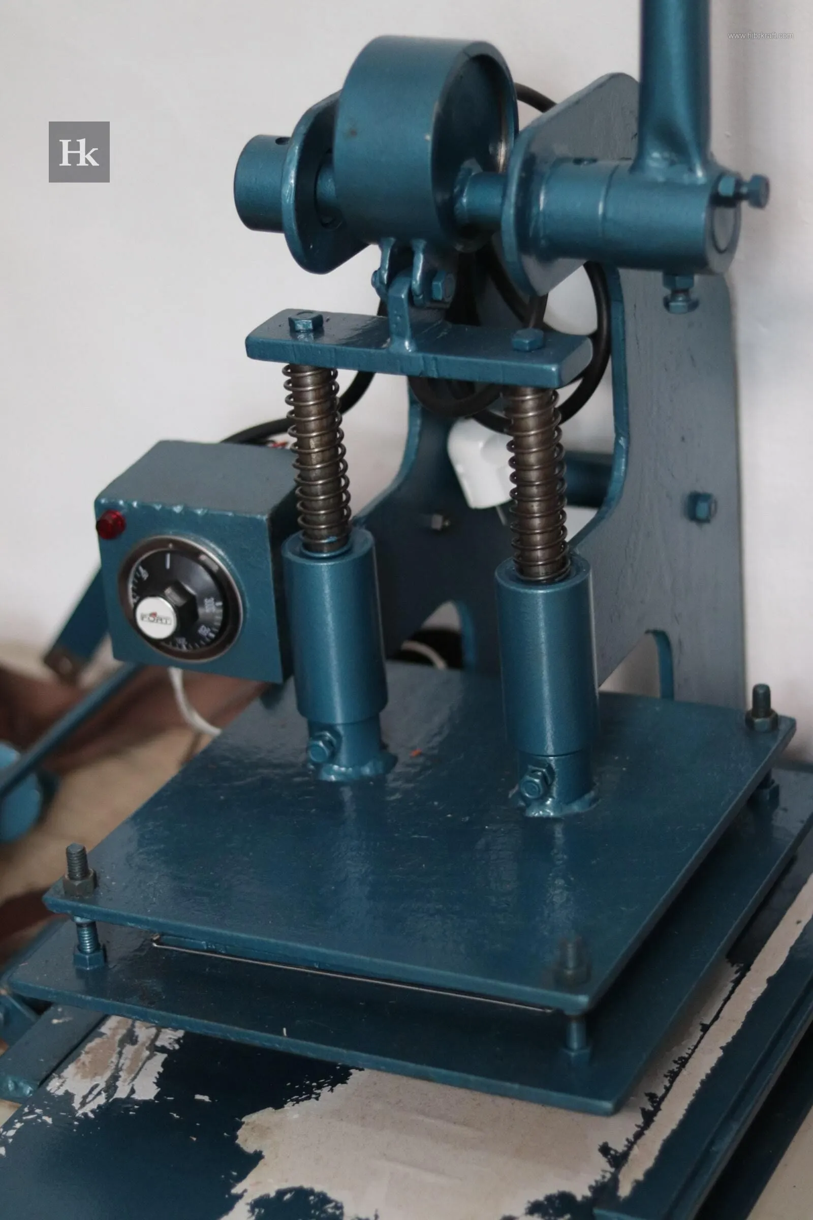 Mesin press hidrolik berwarna biru tua yang kokoh, digunakan untuk stamping, embossing, atau pemasangan perangkat keras pada material.