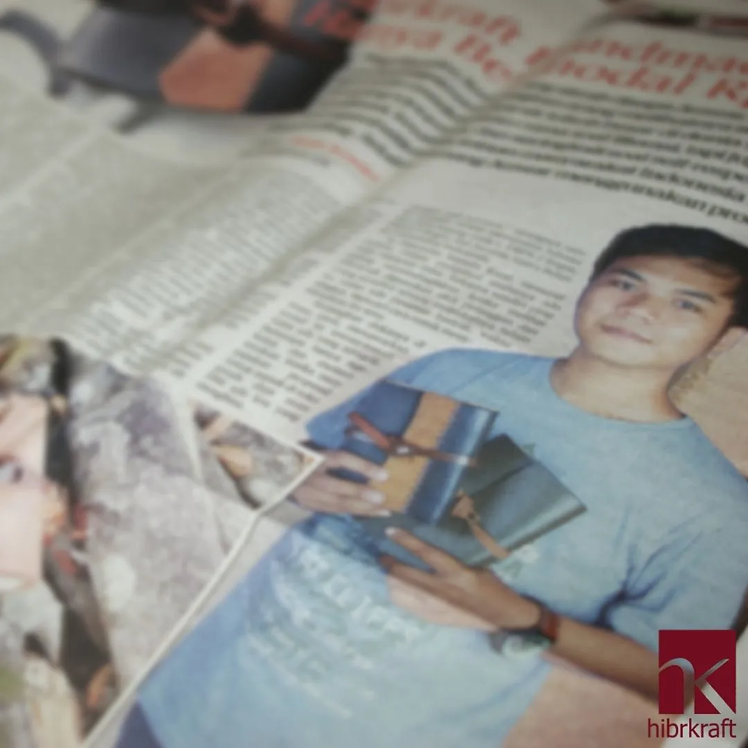 Kliping artikel surat kabar yang menampilkan foto pendiri Hibrkraft memegang beberapa jurnal kulit buatannya.