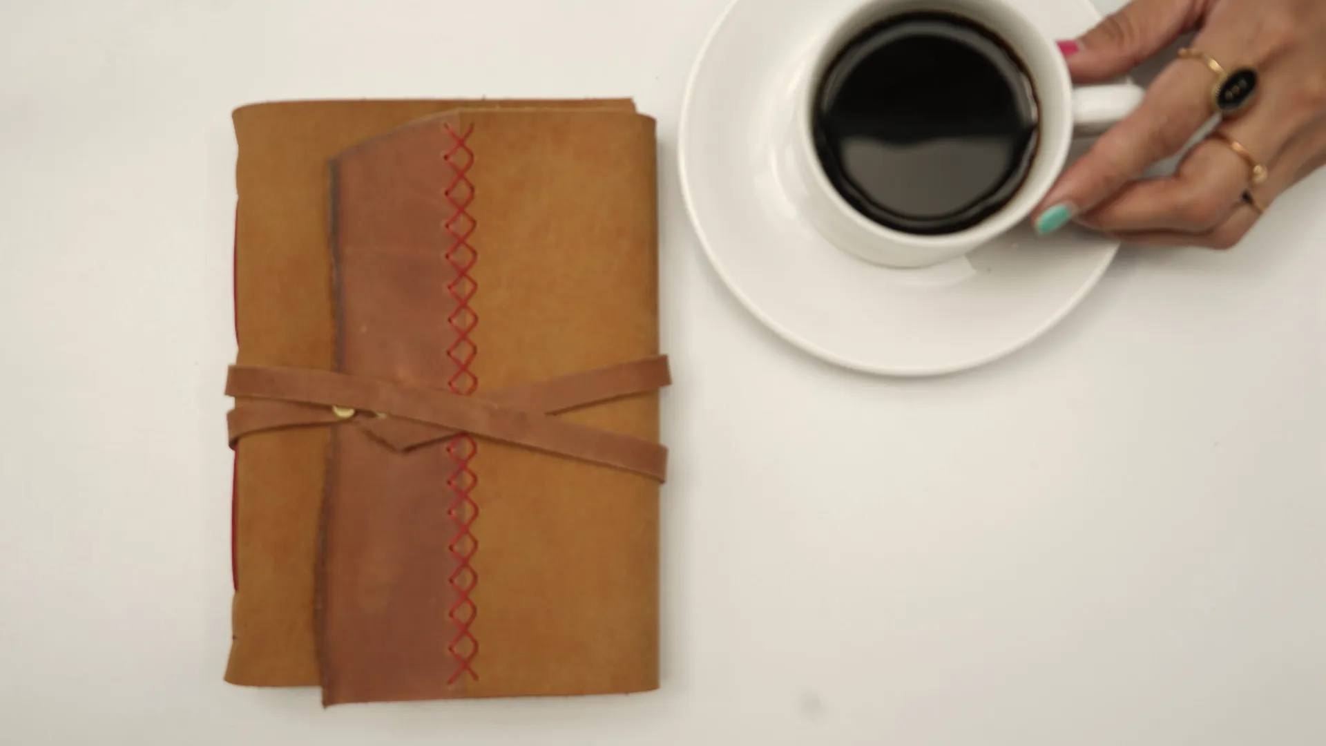 Sebuah jurnal kulit rustic tergeletak di samping secangkir kopi, melambangkan momen personal dan koneksi emosional.
