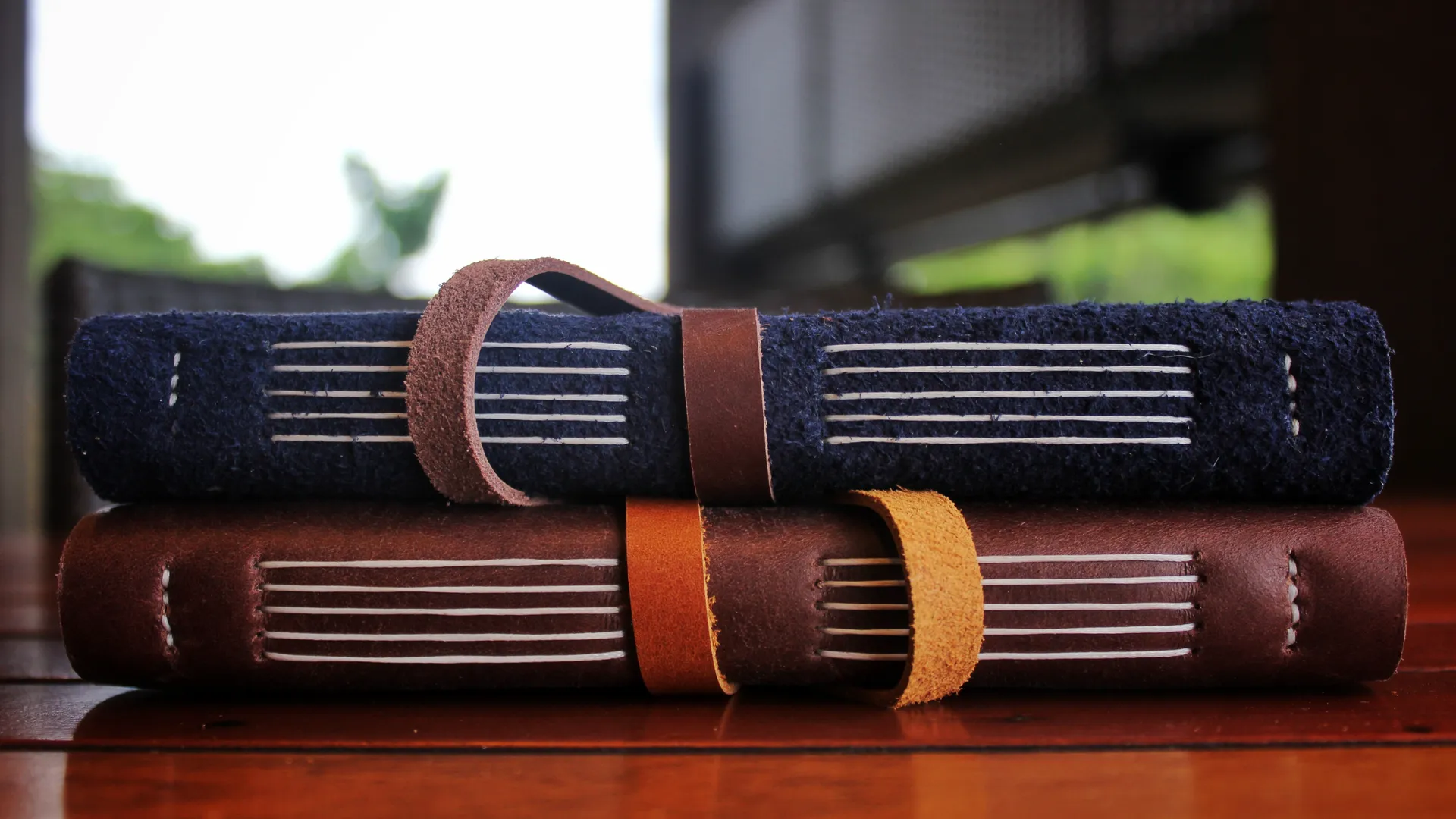 Tumpukan agenda kulit eksklusif dengan jahitan tangan yang rapi, siap untuk dikirimkan sebagai souvenir perusahaan premium.