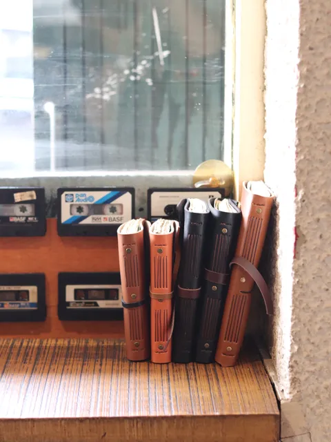 Tumpukan jurnal kulit dengan sampul polos, menunjukkan detail jahitan dan kualitas material kulit.