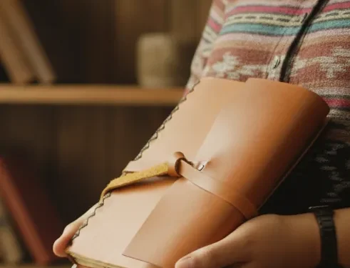 Person Holding Leather Journal Indoors Cozy