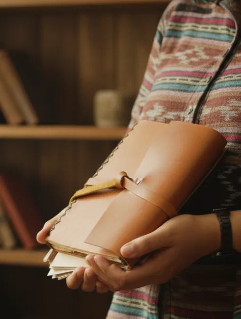 Person Holding Leather Journal Indoors Cozy