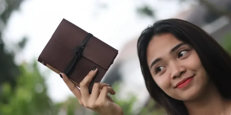 Woman Holding Brown Leather Journal Outside