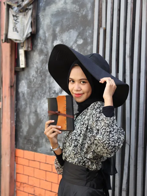Wanita memegang sebuah jurnal kulit yang elegan, yang bisa menjadi pusaka berharga di masa depan.