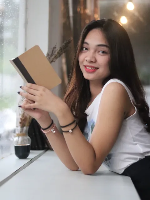 Wanita memegang buku catatan kustom di kafe, menunjukkan sentuhan pribadi dan kualitas premium dari Hibrkraft.