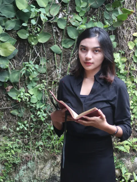 Seorang wanita memegang custom notebook di luar ruangan, menunjukkan jurnal sebagai pendamping dalam setiap perjalanan.