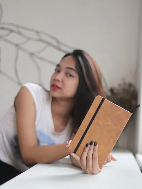 Seorang profesional wanita memegang custom notebook kulit premium yang sering disebut sebagai agenda kulit.