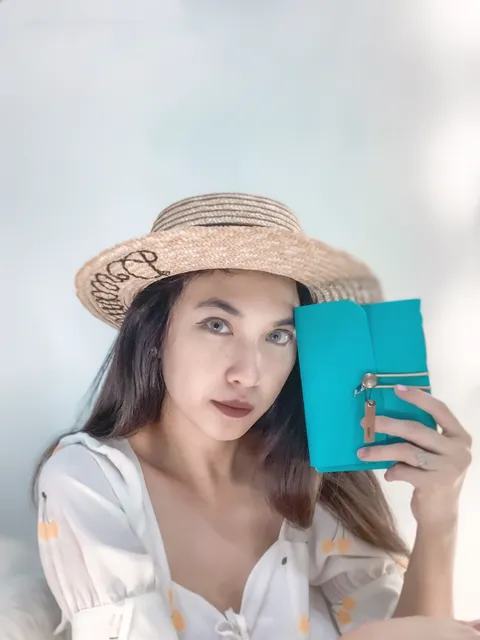 Wanita memegang buku catatan kulit berwarna teal, contoh custom notebook.