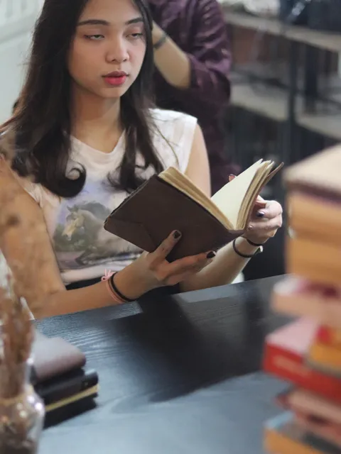 Wanita menulis di jurnal kulit custom di meja