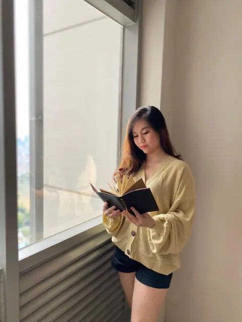 Wanita membaca jurnal kustom yang dipersonalisasi di dekat jendela, menunjukkan relevansi produk personalisasi.