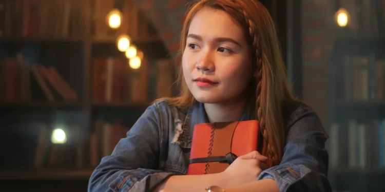 Young Woman Holding Book In Library
