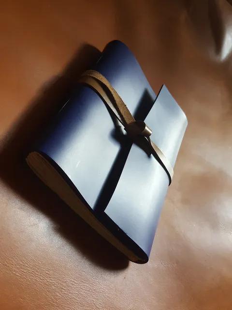 Buku catatan kulit berwarna biru yang terawat baik, menunjukkan keindahan material.