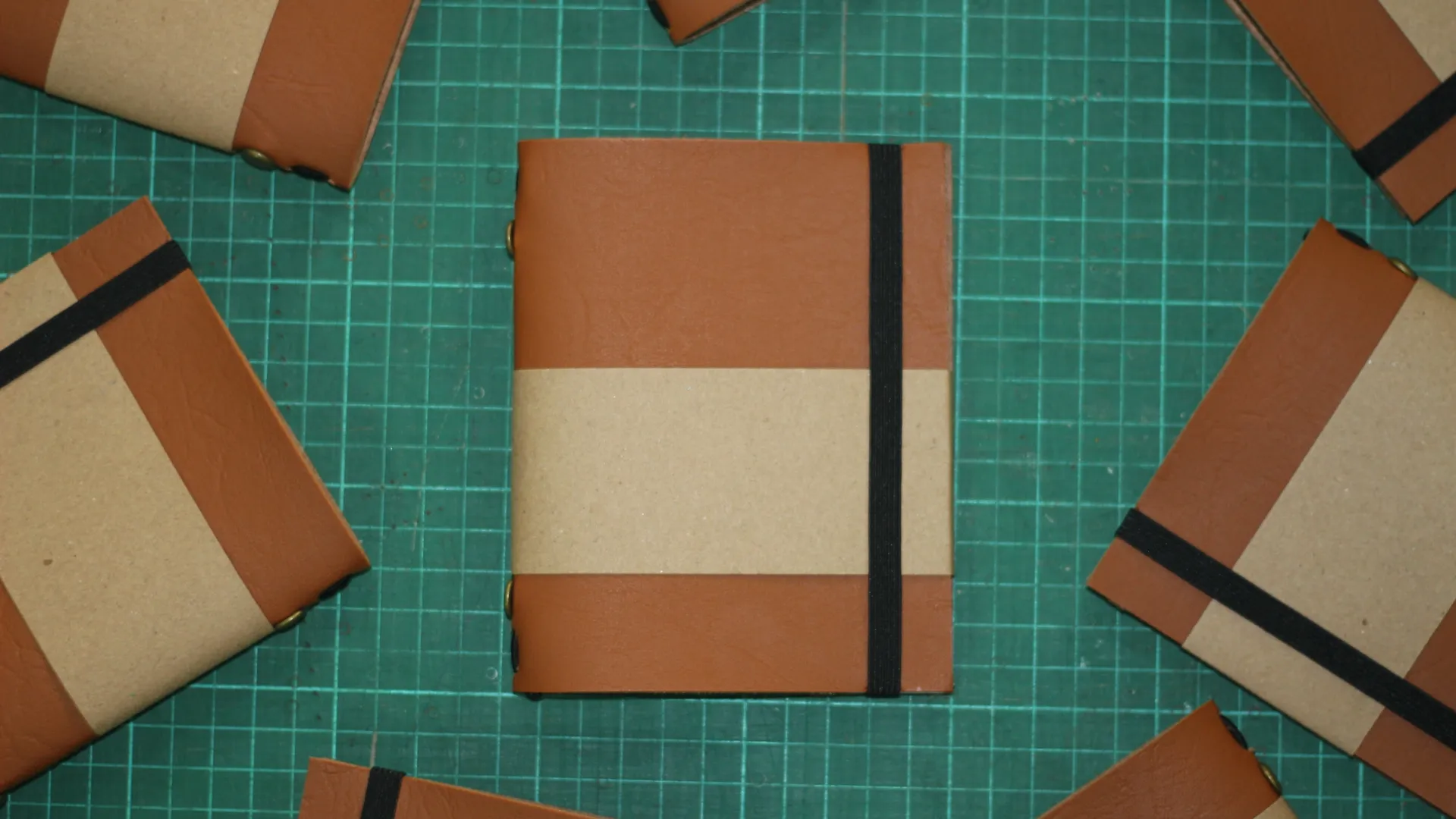 Beberapa jurnal kulit berwarna coklat kraft ditumpuk bersama, menunjukkan estetika rustic yang cocok untuk buku resep.