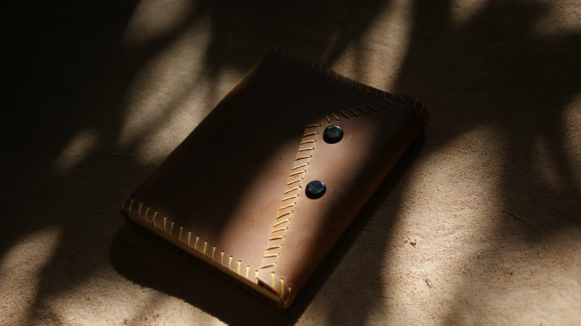 Detail jahitan tangan pada jurnal kulit coklat, menunjukkan kualitas pengerjaan yang tinggi.