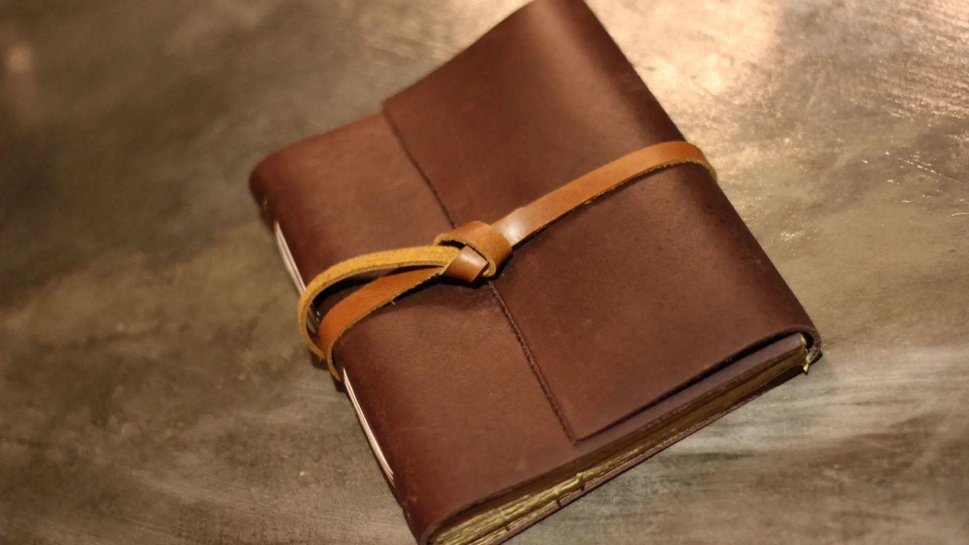 Sebuah jurnal kulit coklat yang kokoh tergeletak terbuka, siap untuk diisi dengan resep-resep berharga.