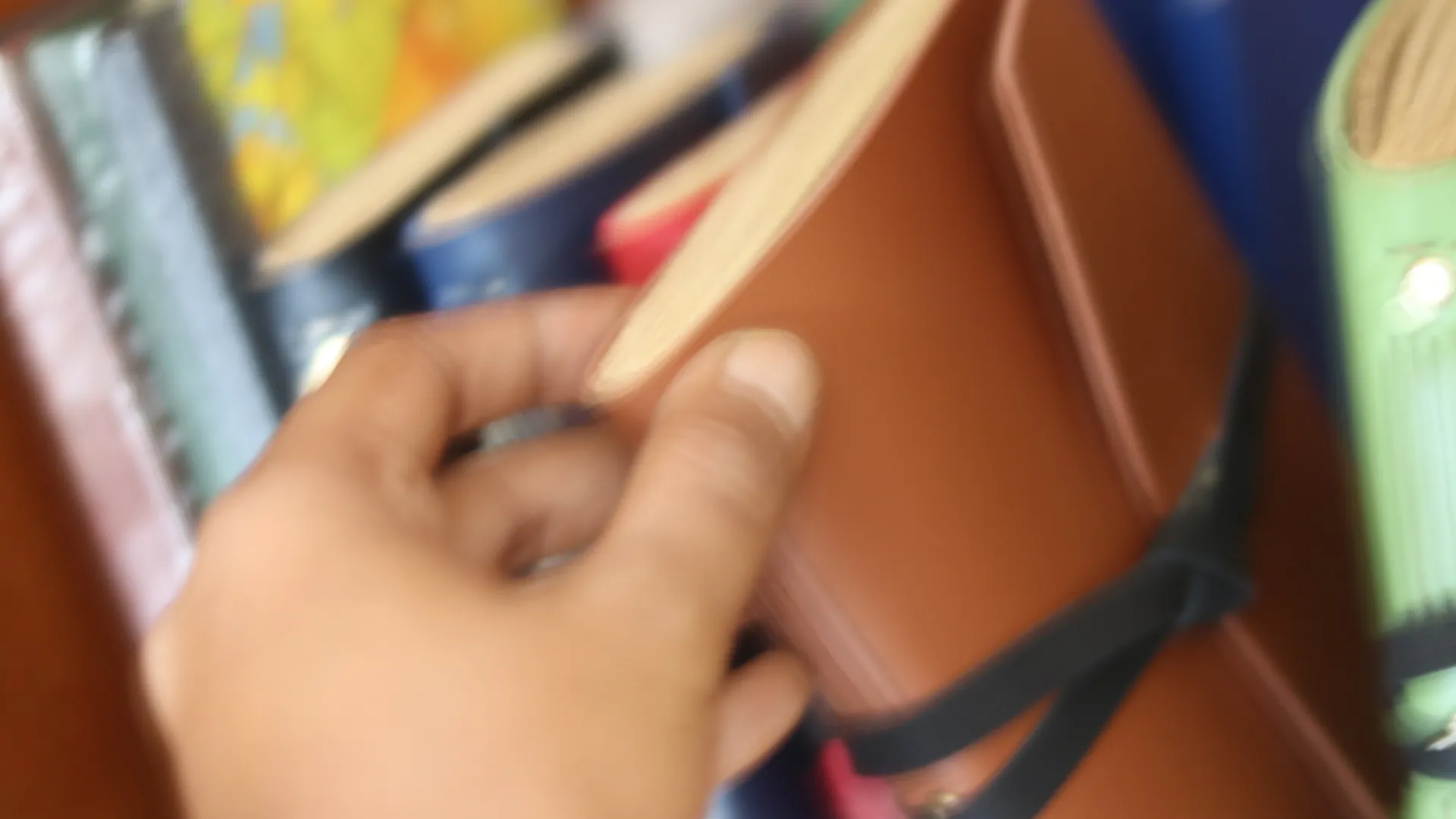 Sebuah jurnal kulit coklat yang elegan dipegang dengan lembut, melambangkan keintiman dan inspirasi.