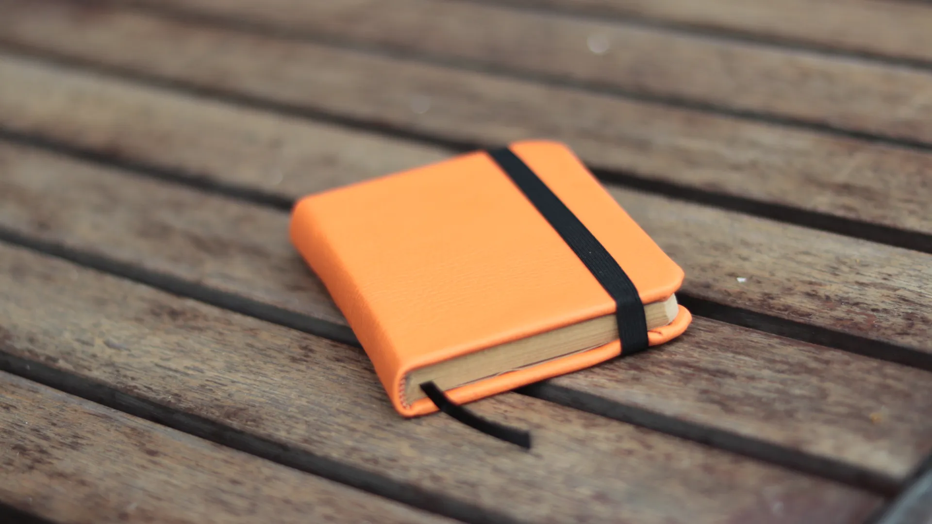 Detail penutup elastis pada jurnal kulit oranye, fitur penting untuk profesional yang sering bepergian seperti arsitek.