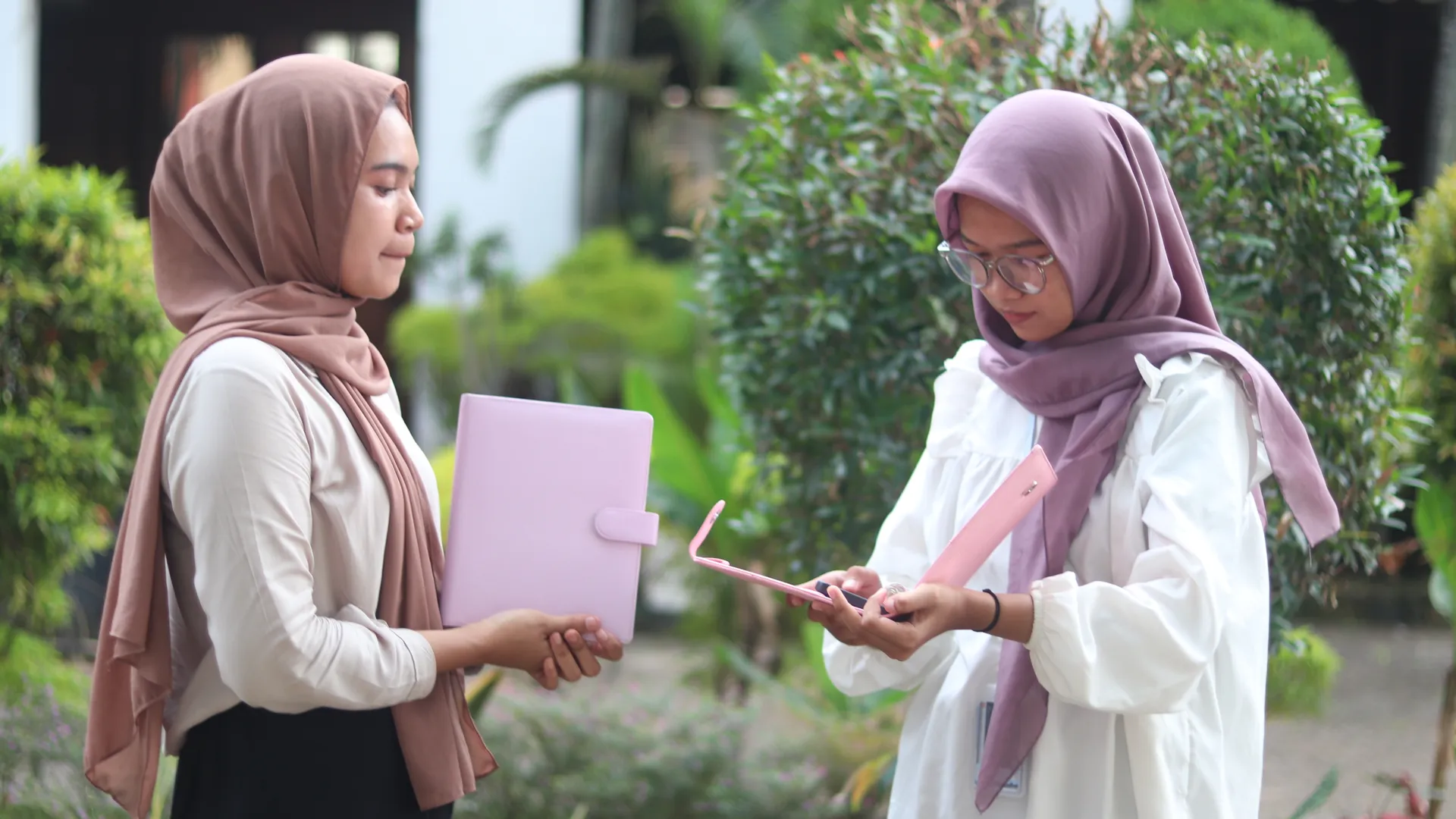 Dua wanita berdiskusi tentang buku catatan custom berwarna pink, memilih hadiah yang tepat untuk seorang penulis.