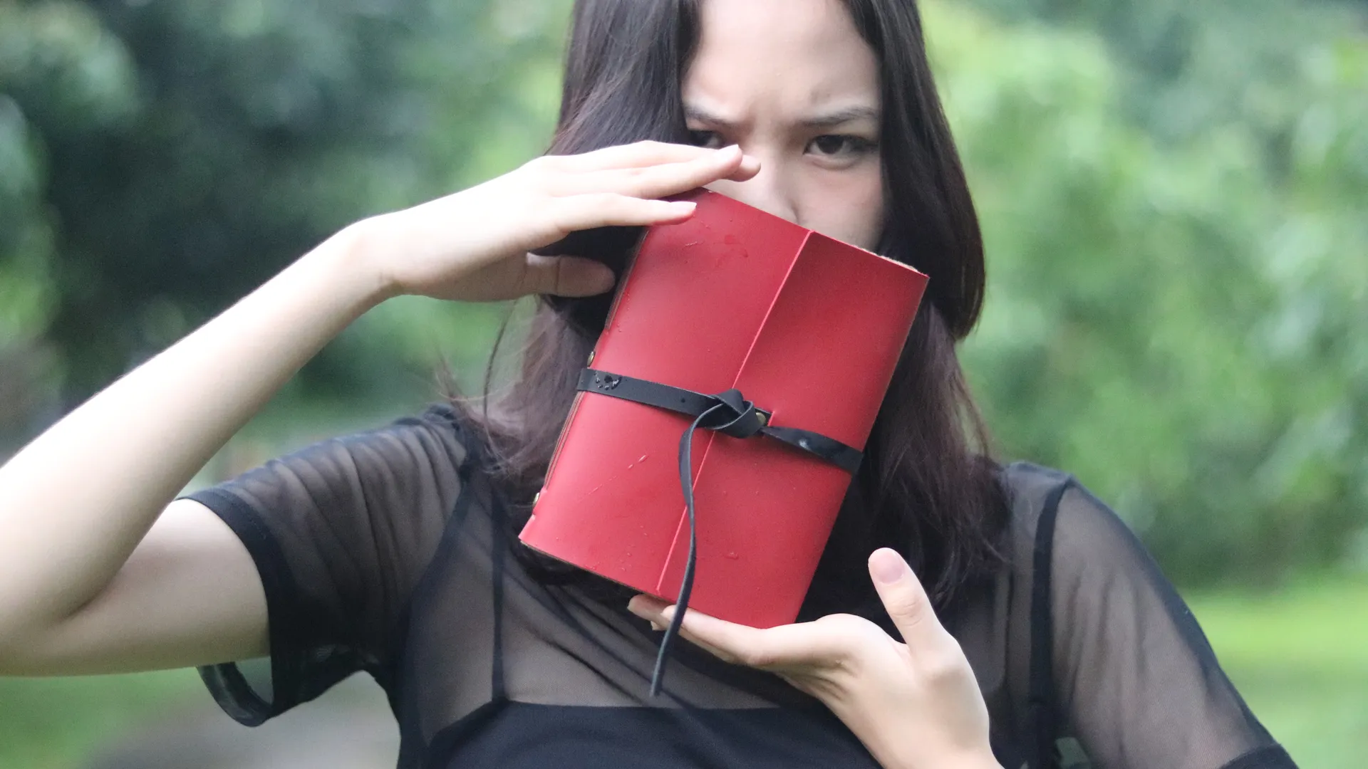 Seorang urban sketcher memegang jurnal kulit merahnya, menunjukkan detail dan kualitas buku tersebut.