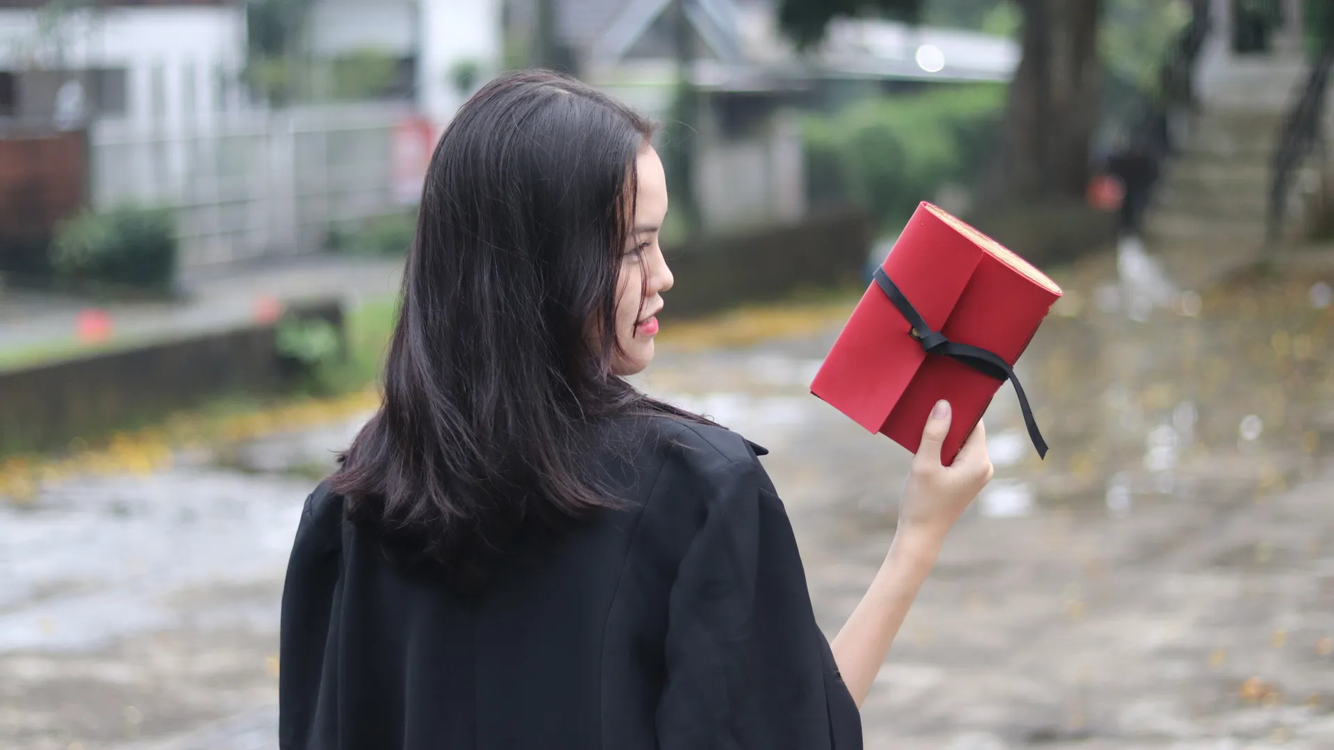 Seorang wanita urban sketcher duduk di taman dengan jurnal kulit merahnya, siap untuk menggambar.