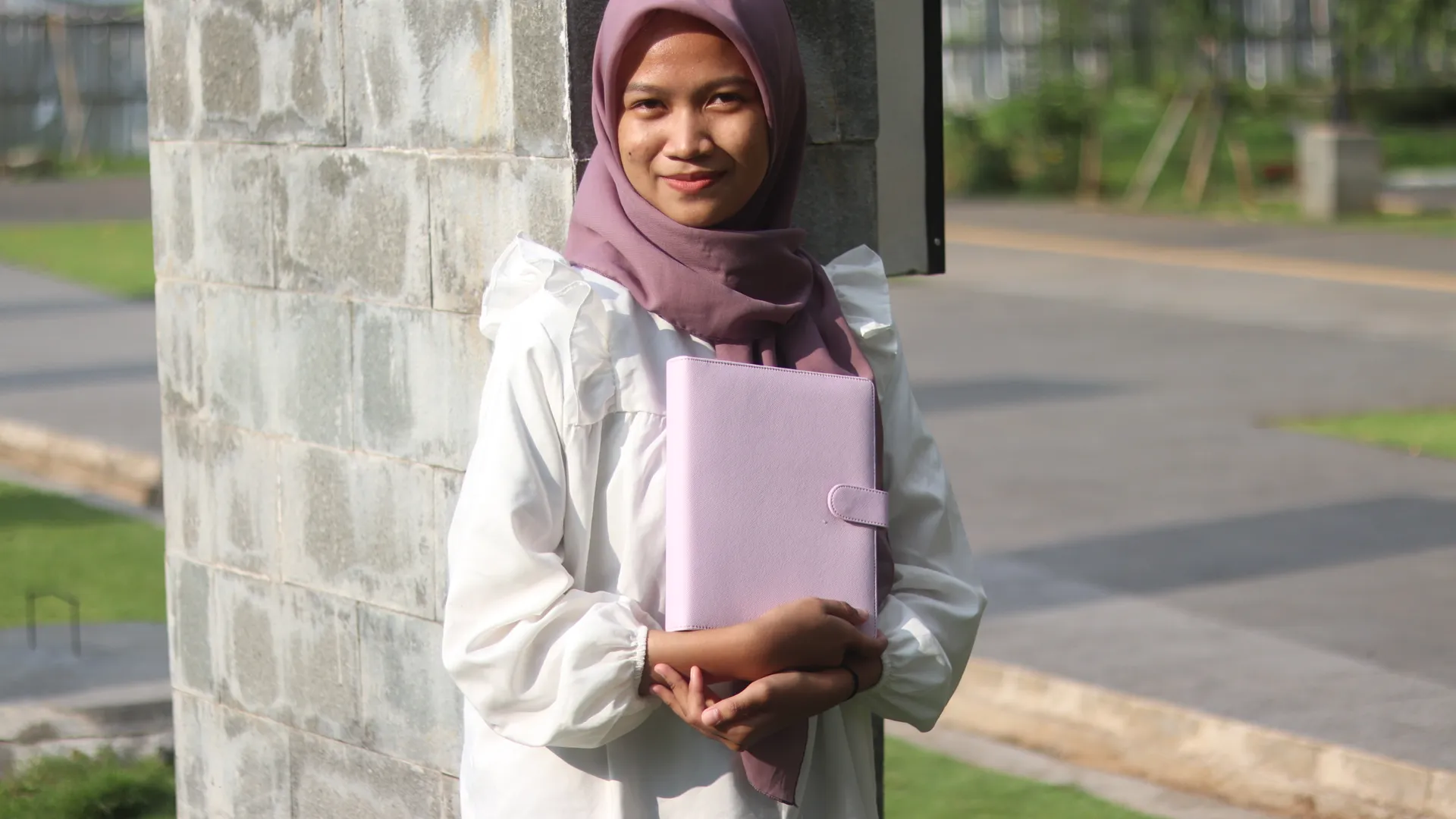 Seorang penulis novel memegang jurnal lavender miliknya dengan bangga, siap menulis karya besarnya.