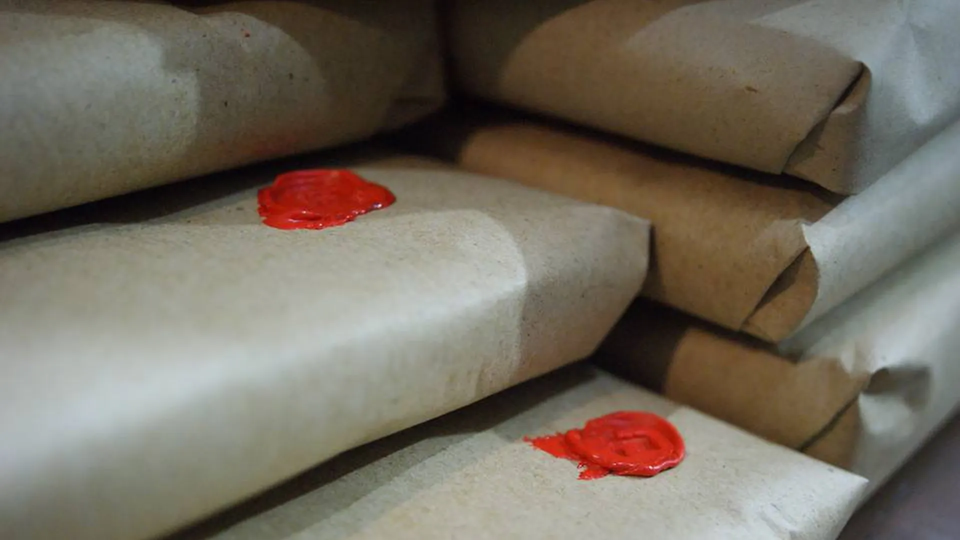 Beberapa jurnal yang dibungkus dengan elegan dan disegel dengan lilin merah, menunjukkan presentasi hadiah yang premium.