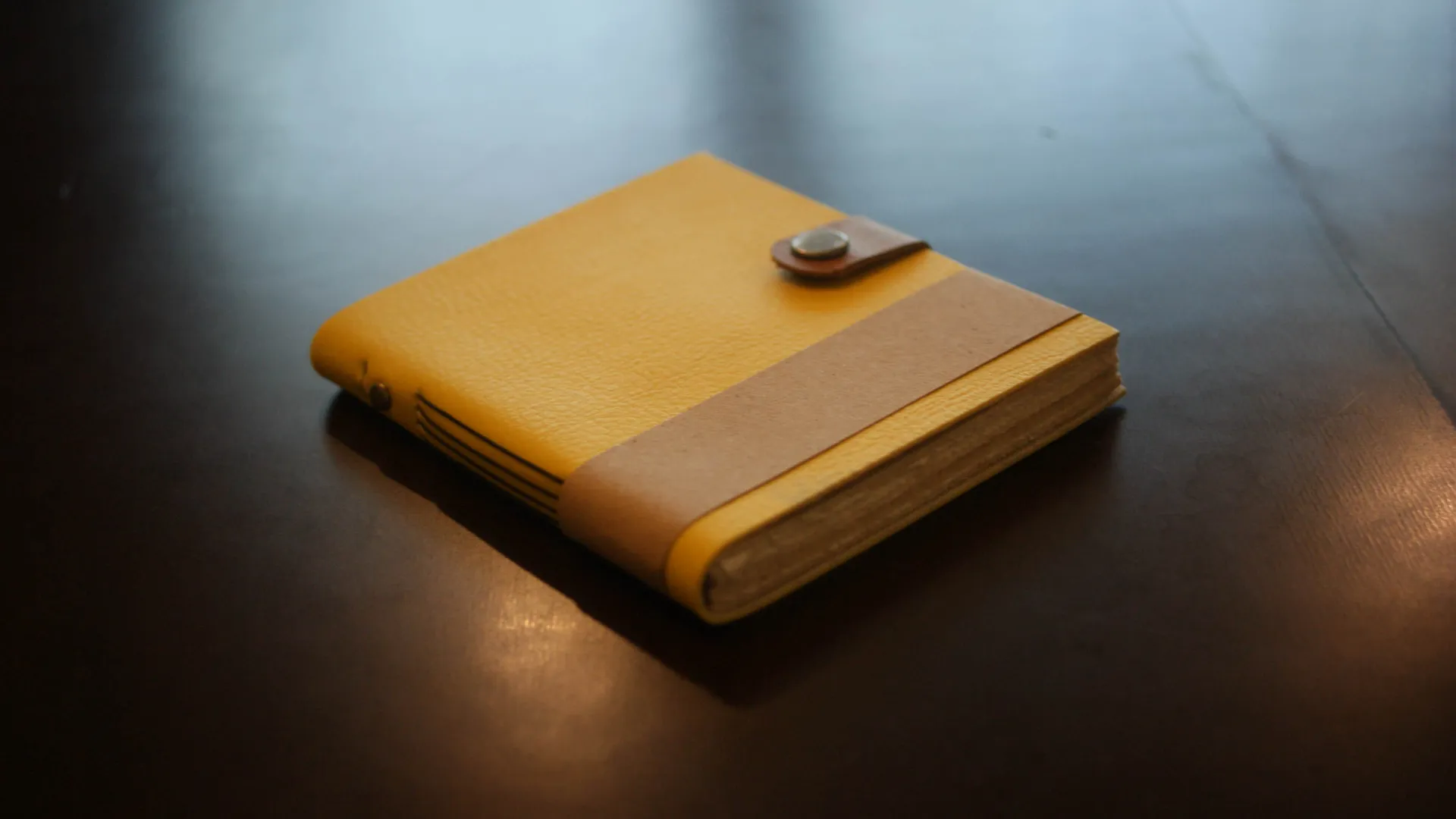 Jurnal kulit berwarna kuning cerah, pilihan yang stylish dan inspiratif untuk seorang desainer grafis.