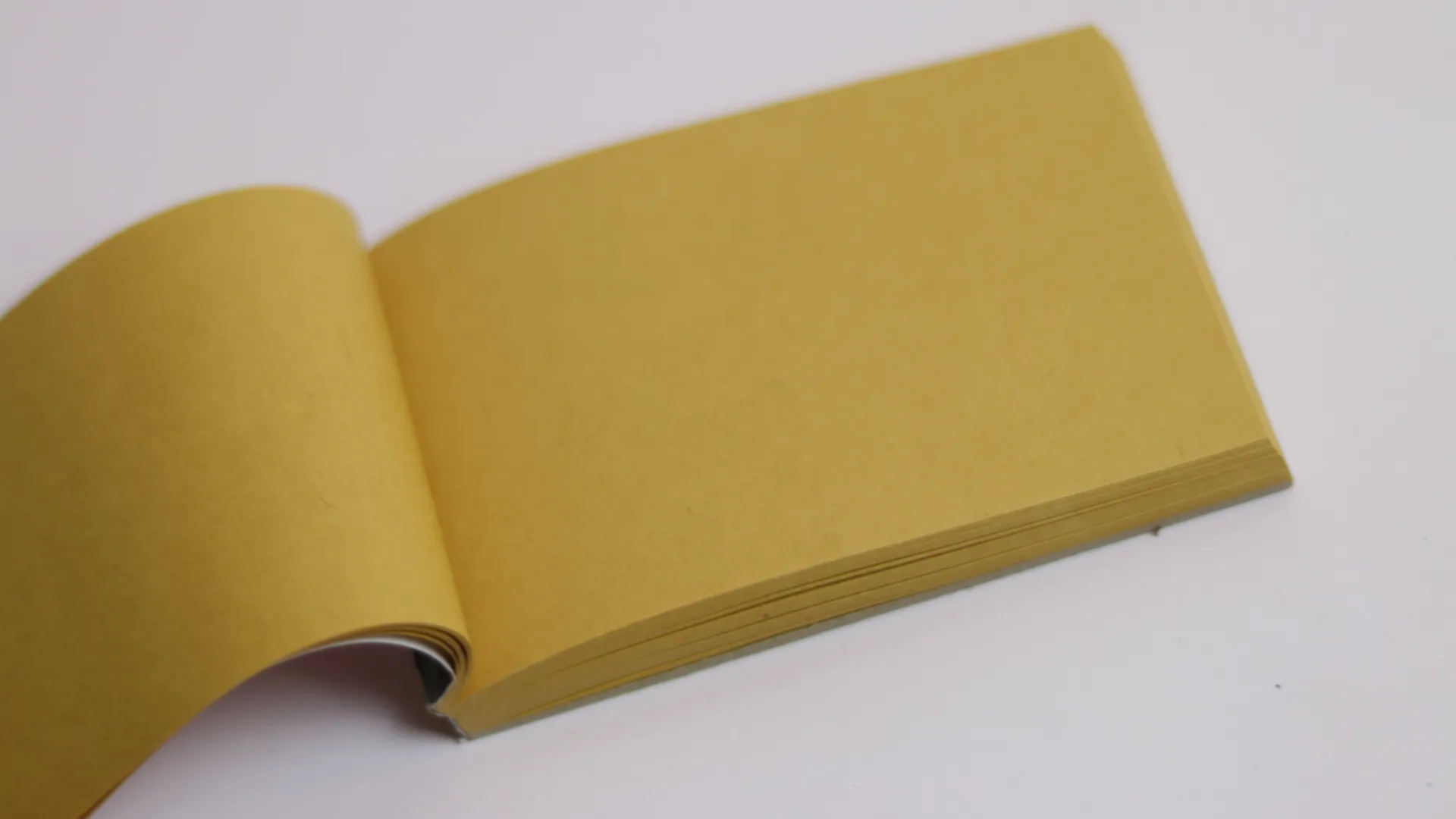 Sebuah jurnal kulit kuning berformat persegi kecil, pilihan unik yang merangsang kreativitas desainer.