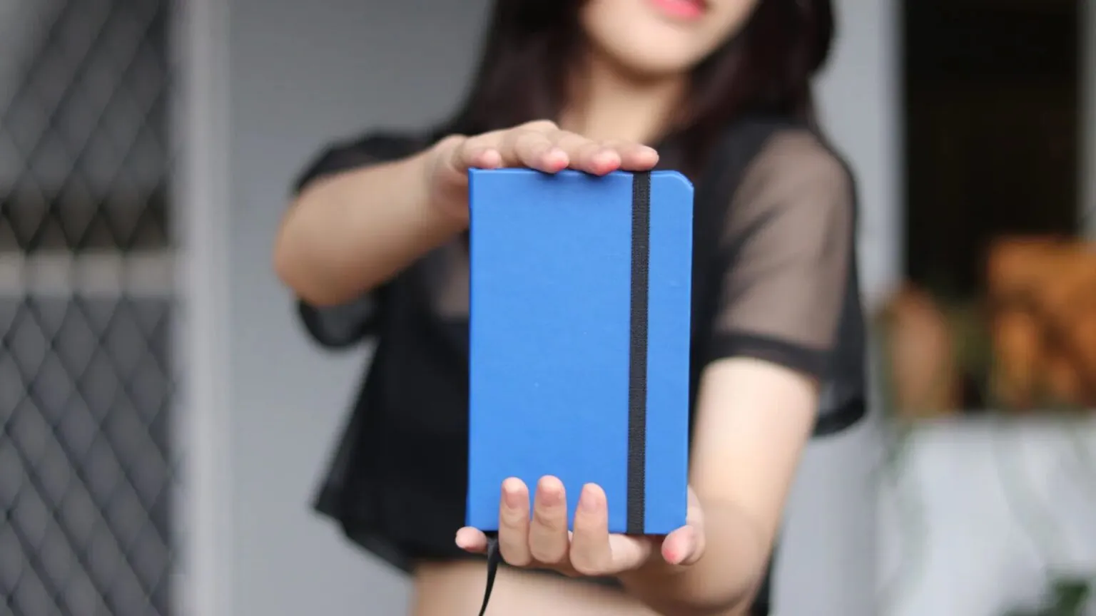 Seorang pelanggan mengangkat jurnal kulit biru buatan Hibrkraft ke arah kamera