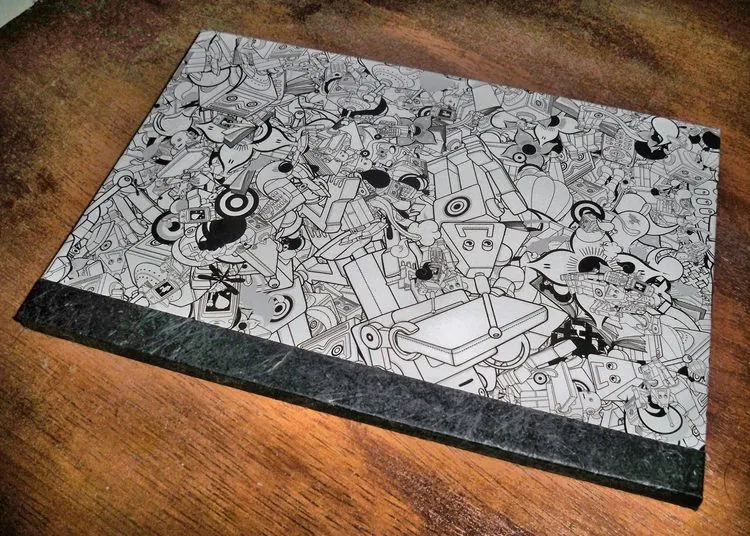 Notebook with a dense black-and-white illustrated cover pattern of stylised robot and cartoon figures, bound with a dark marbled-look spine