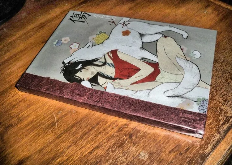 Quarter-bound journal with a printed illustration cover, a dark-haired figure resting against a large white fox, bound in maroon cloth
