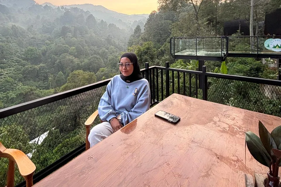 Elsa Helmia Puteri duduk di teras kayu dengan latar perbukitan Bogor saat matahari terbit