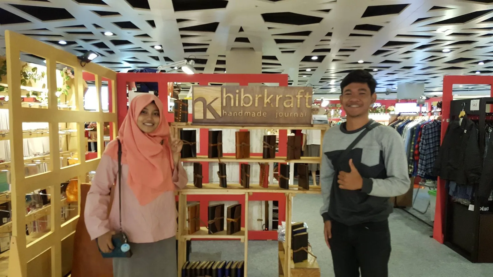 A Hibrkraft stall with a wooden sign reading hibrkraft handmade journal and shelves of leather journals