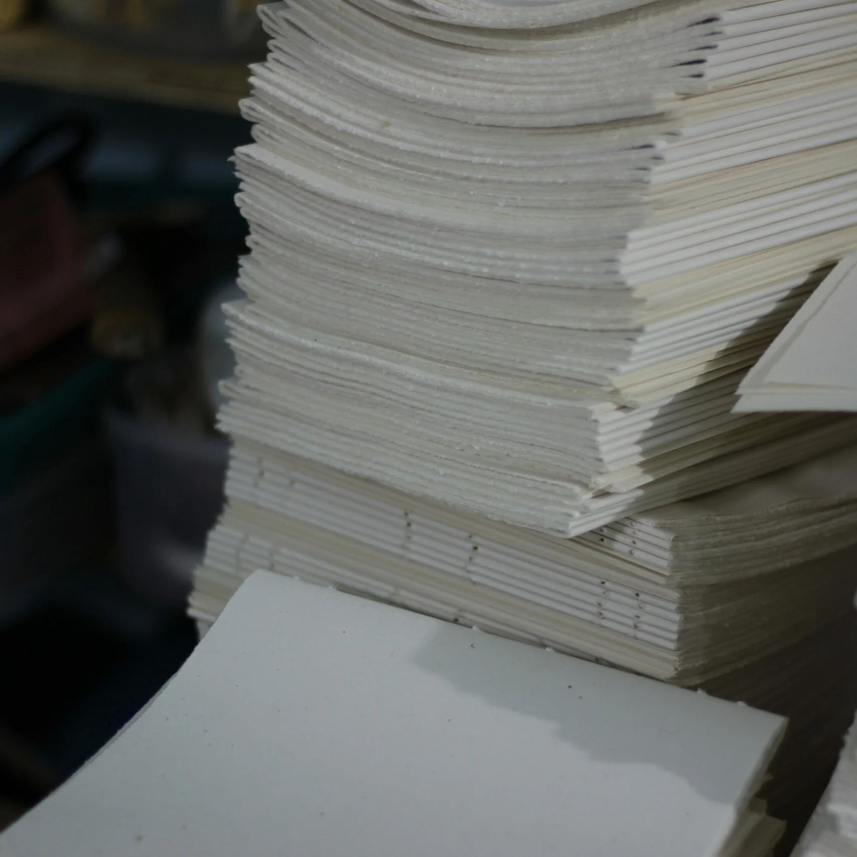 Tumpukan lipatan kertas yang sudah dilubangi, siap dijahit