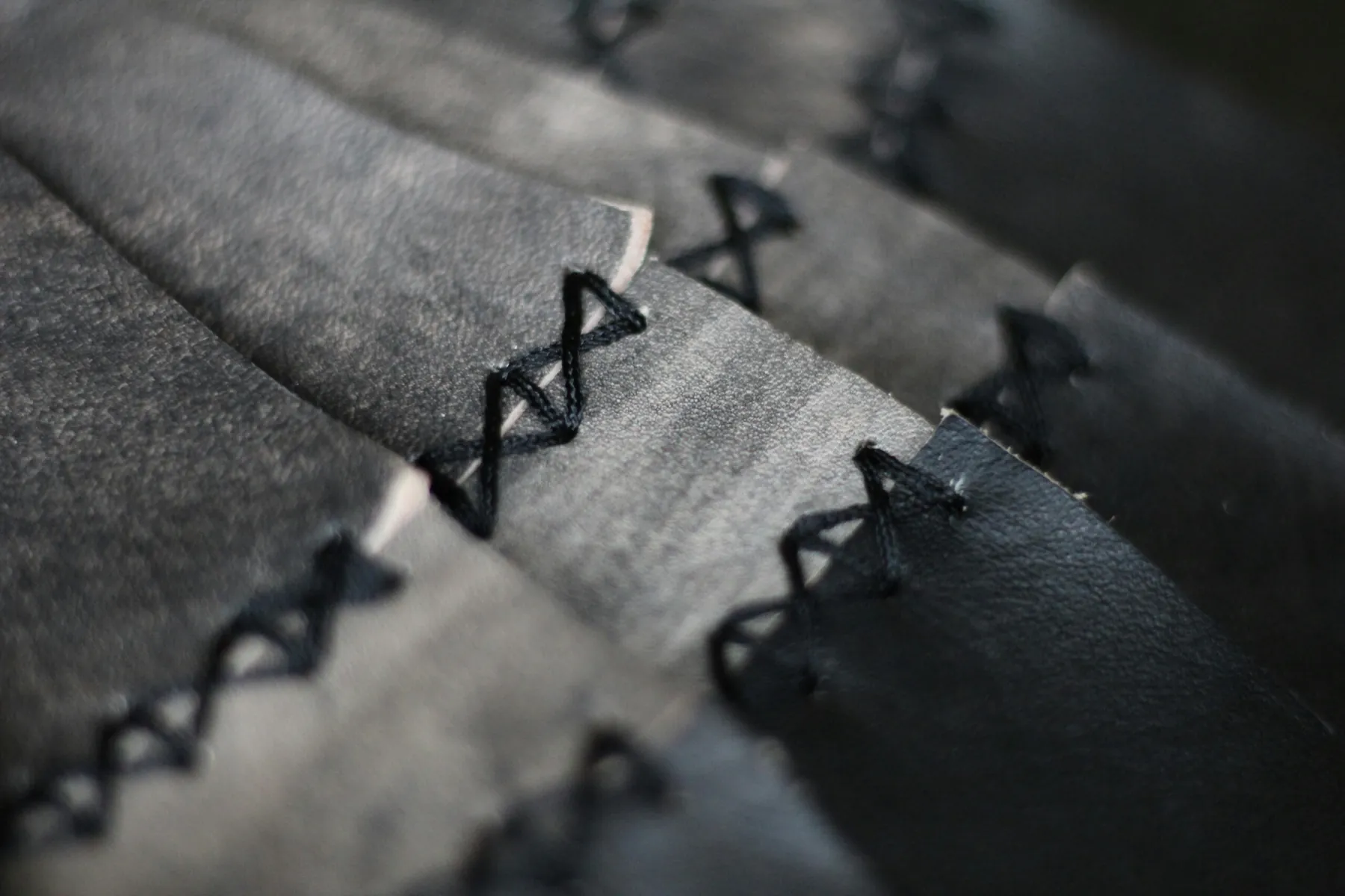 A close view of black cross-stitching joining pieces of black leather along their edge