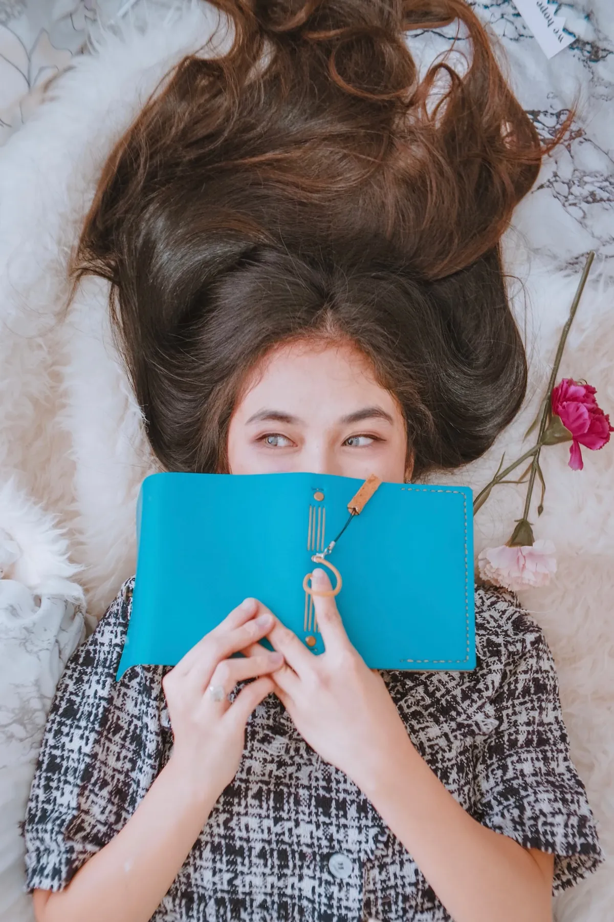 Someone holding a teal blue leather journal with hand stitching and a tie closure