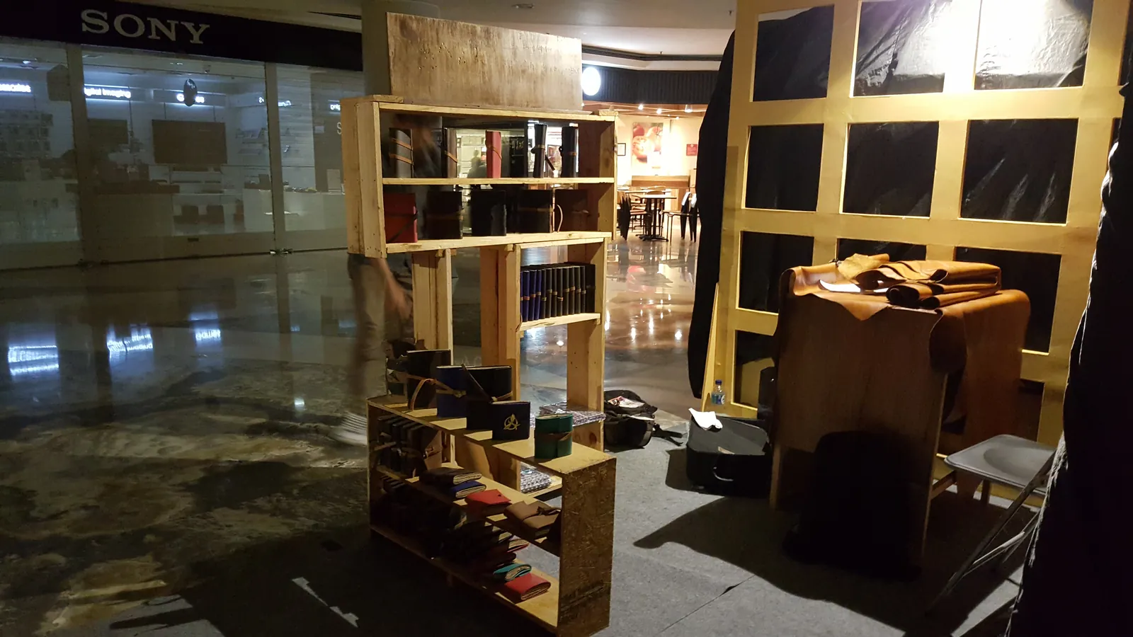 A Hibrkraft pop-up stand with wooden shelves of leather goods inside a shopping centre