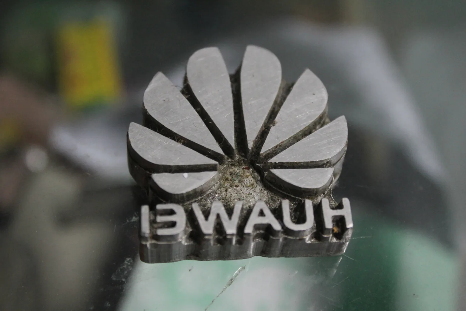 Pelat deboss logam berlogo Huawei, huruf terbaca terbalik karena pelat dibubut mirror
